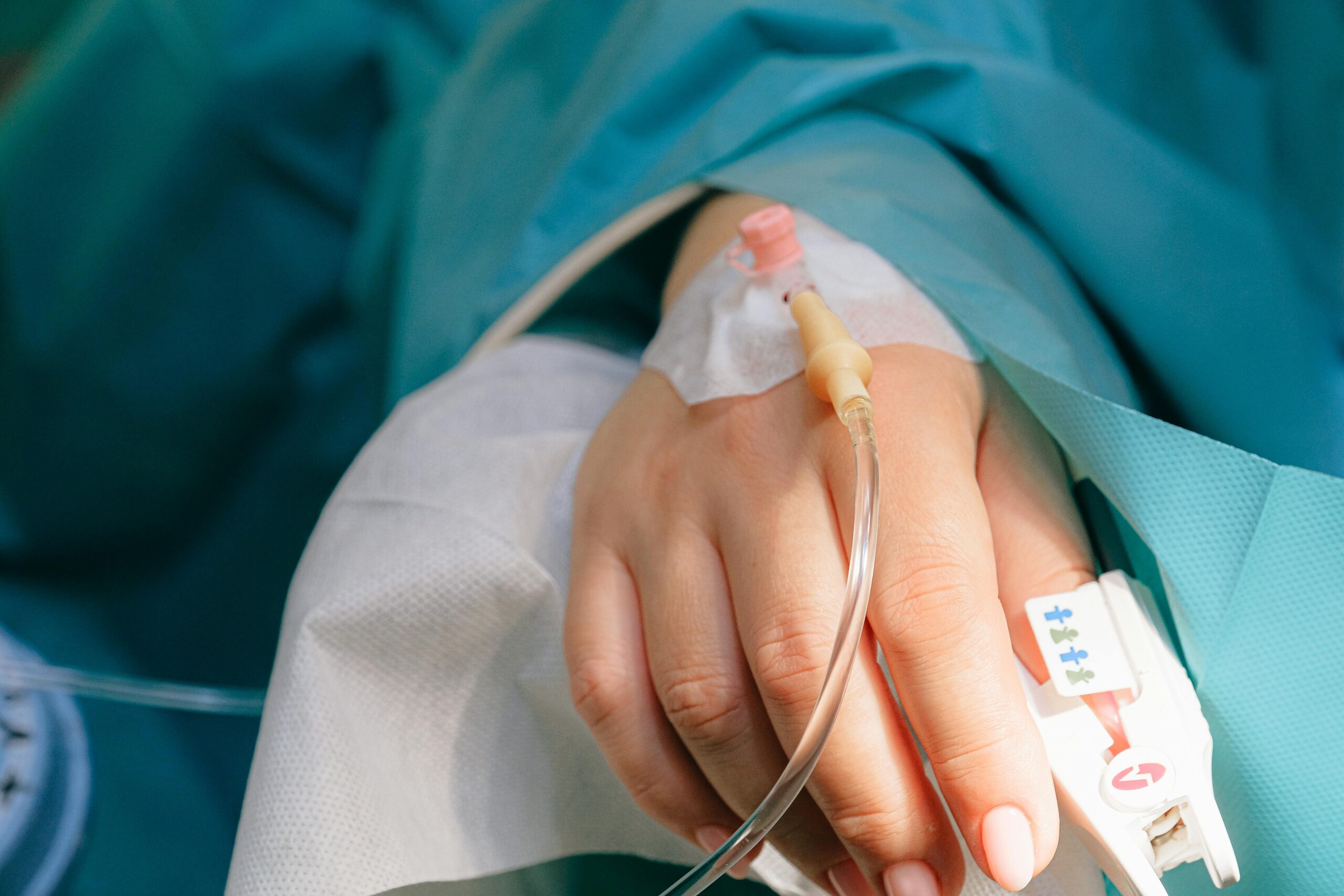 Close-up of a patient's hand with intravenous therapy and pulse oximeter, symbolizing healthcare and treatment.