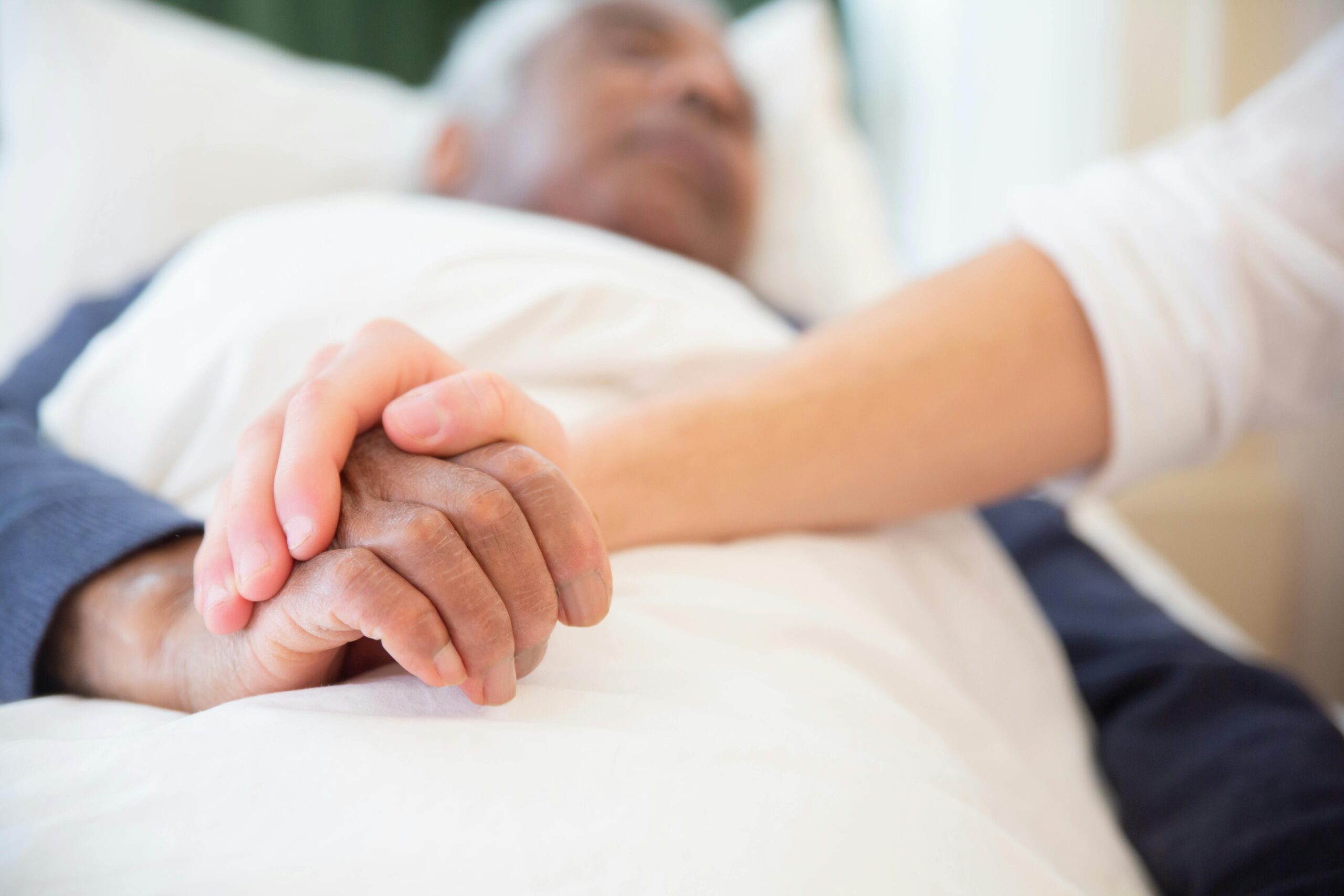 A comforting gesture as a hand holds another in a hospital setting, symbolizing care and support.