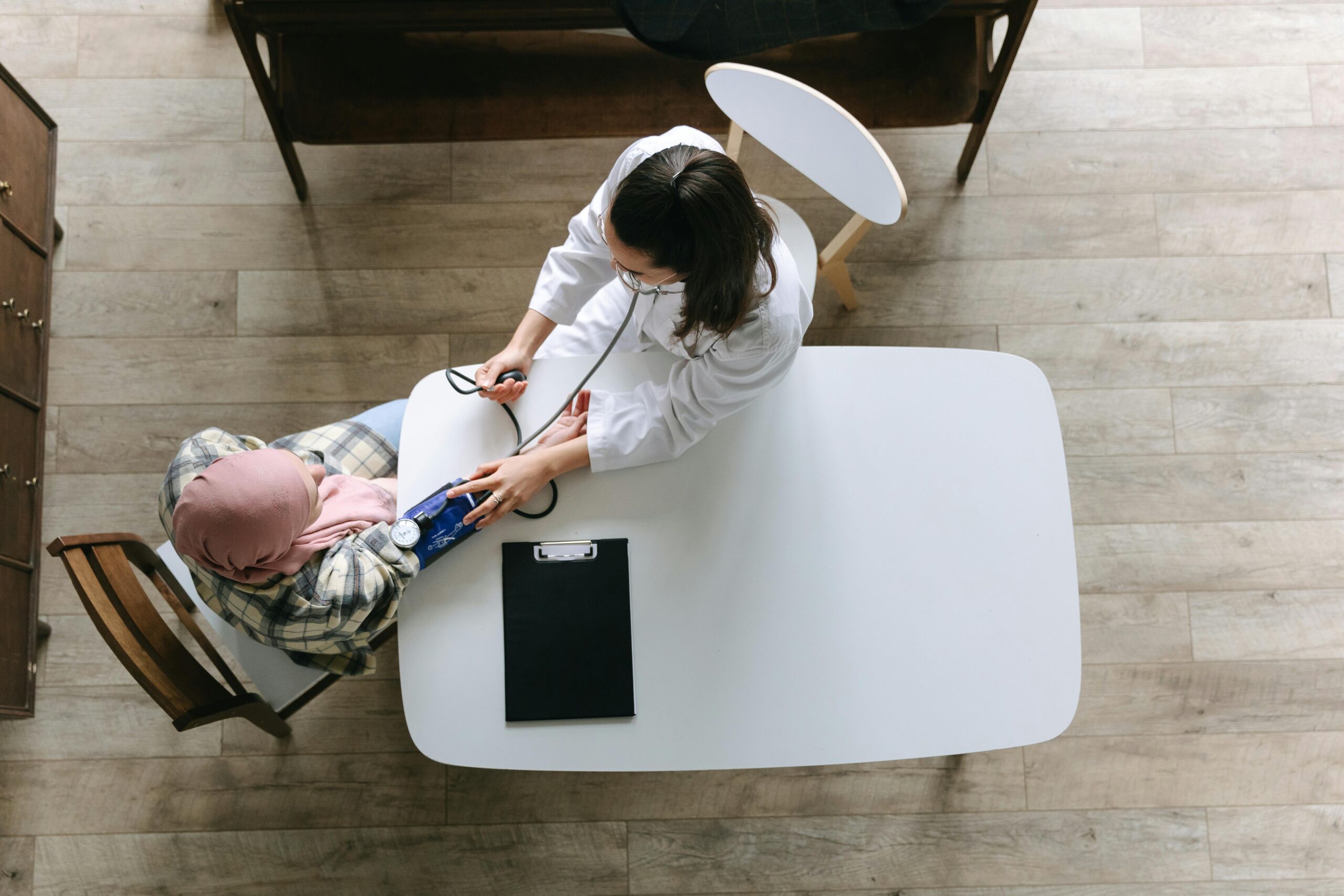 Overhead view of a doctor checking a patient's blood pressure during a healthcare consultation indoors.